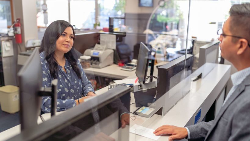 A woman doing a transaction with a bank teller inside a banking hall