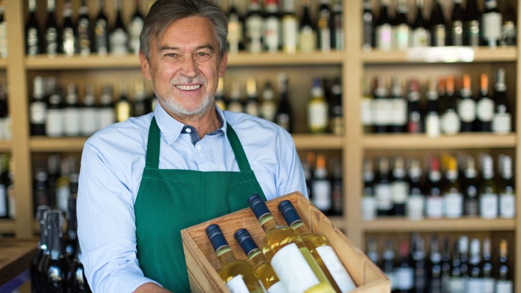 Liquor store owner posing with some of his bestselling wine