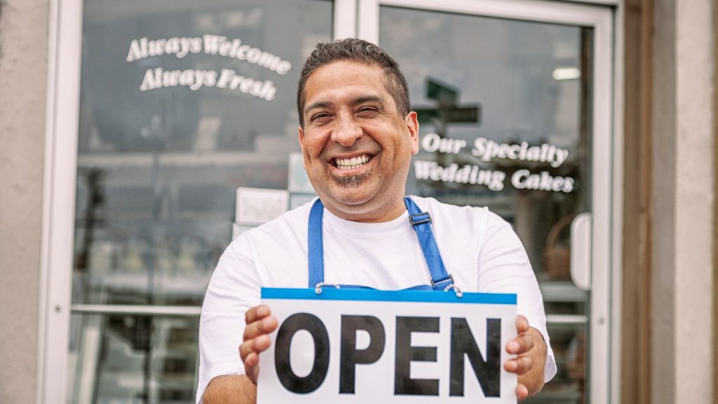 Restaurant owner smiling in front of his shop